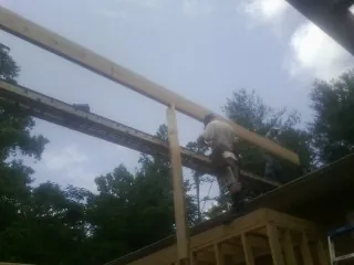 Carpenter setting a ridge beam over a new addition frame — Ice Dam Removal by Roofing Brothers in Cabins