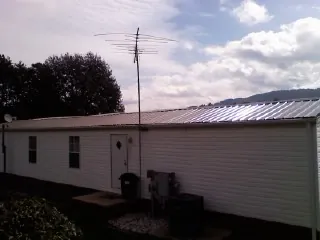 New metal roof on a single wide mobile home with a TV antenna in Cabins