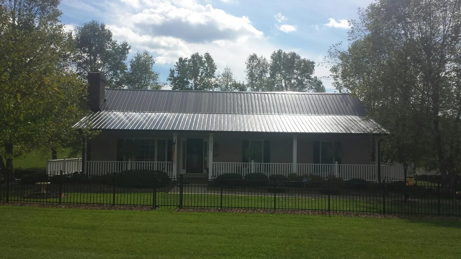 Gray metal roof on a brick ranch with a full width front porch — Gutter Guard Installation work by our crew in Cabins