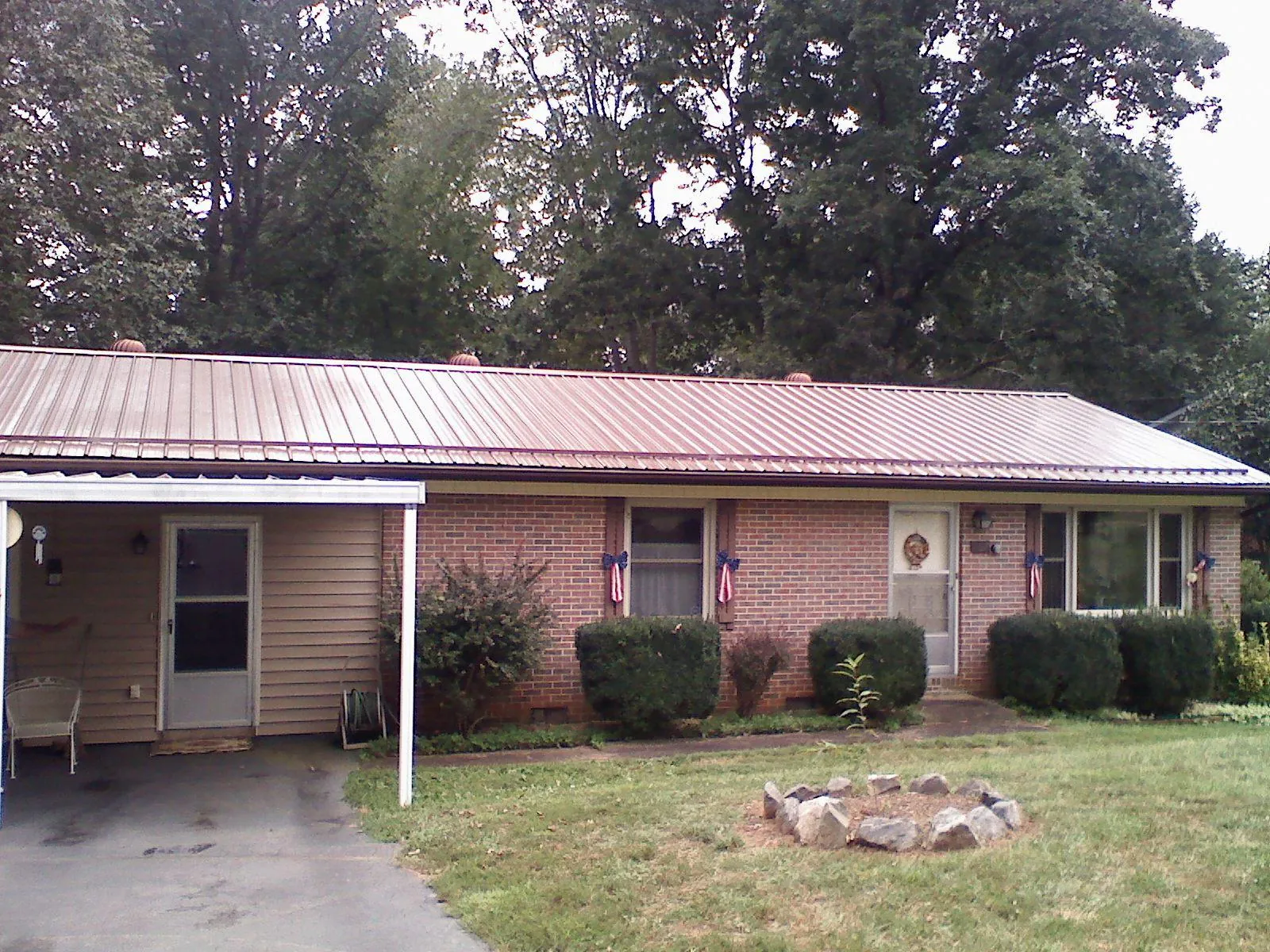 Bronze metal roof and carport on a brick ranch home — Roof Repair work by our crew in Cabins